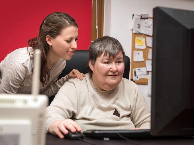 Caregiver and mentally disabled woman learning at the computer. (Shutterstock)