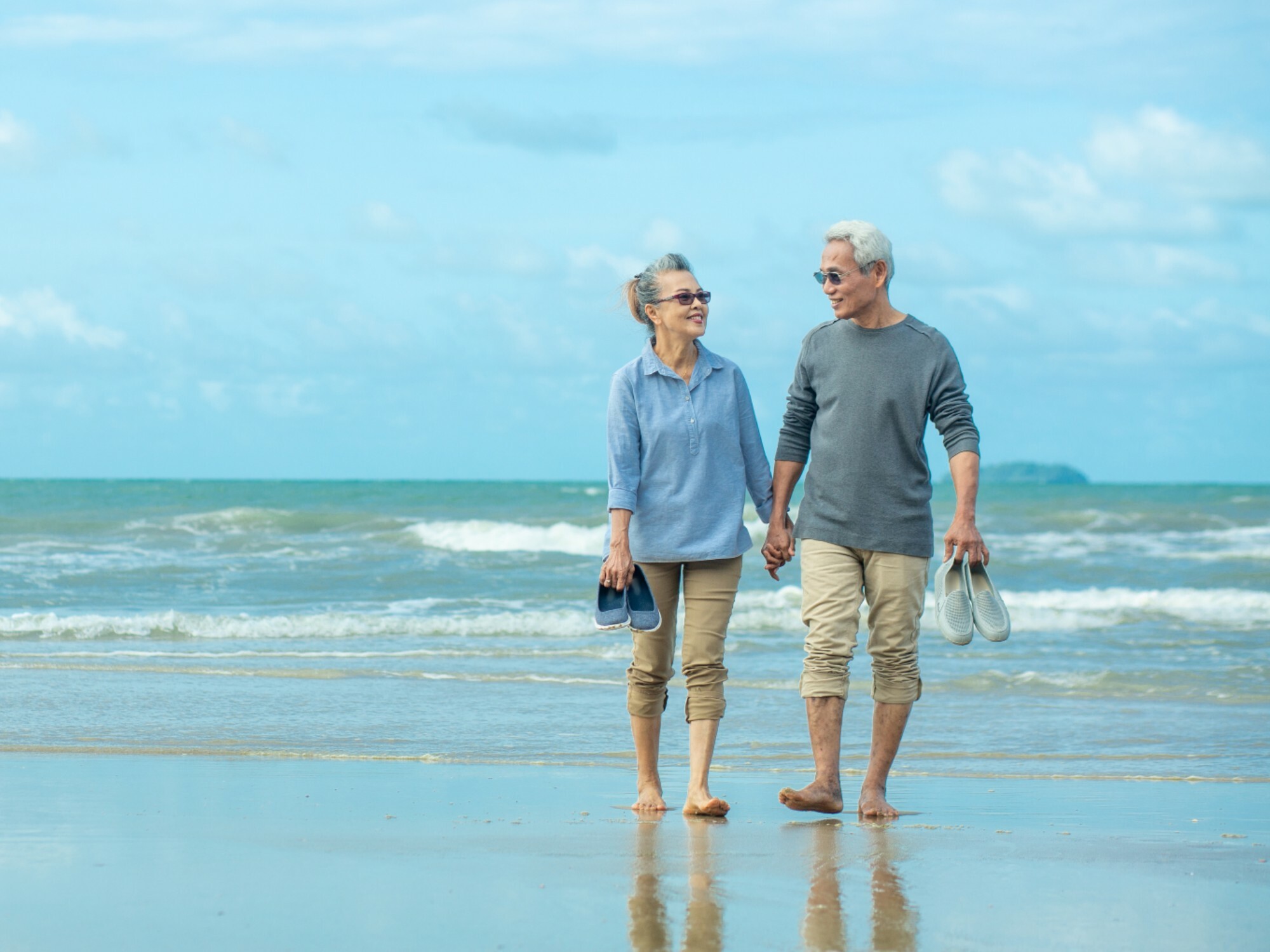 Older couple walking on the beach together