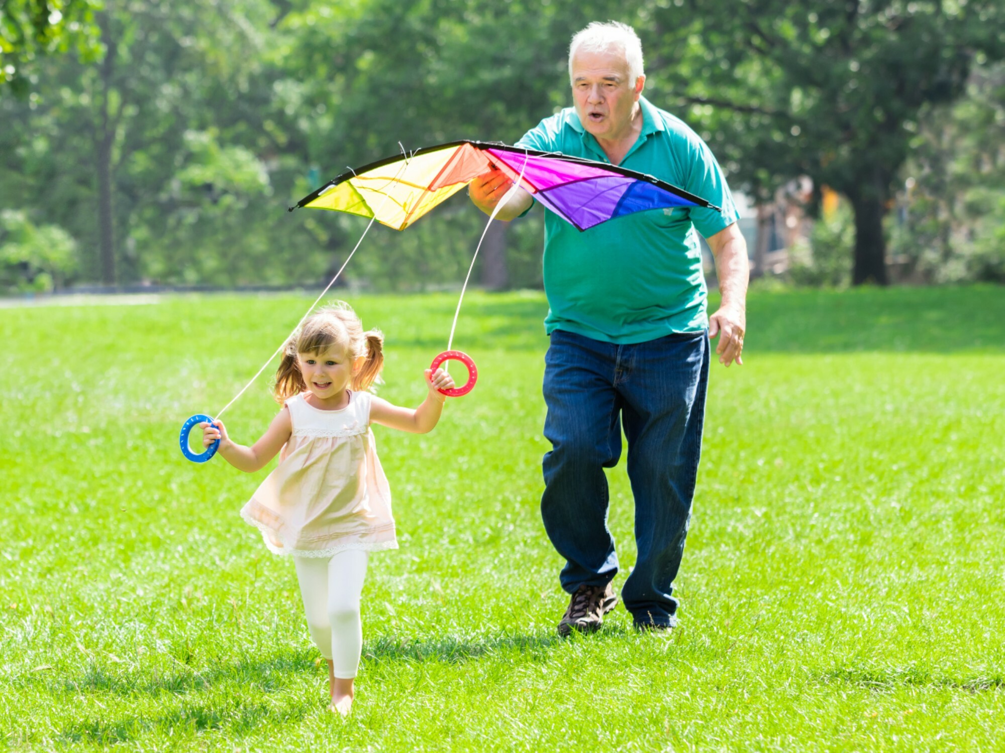Grandfather and granddaughter playing with a kite together